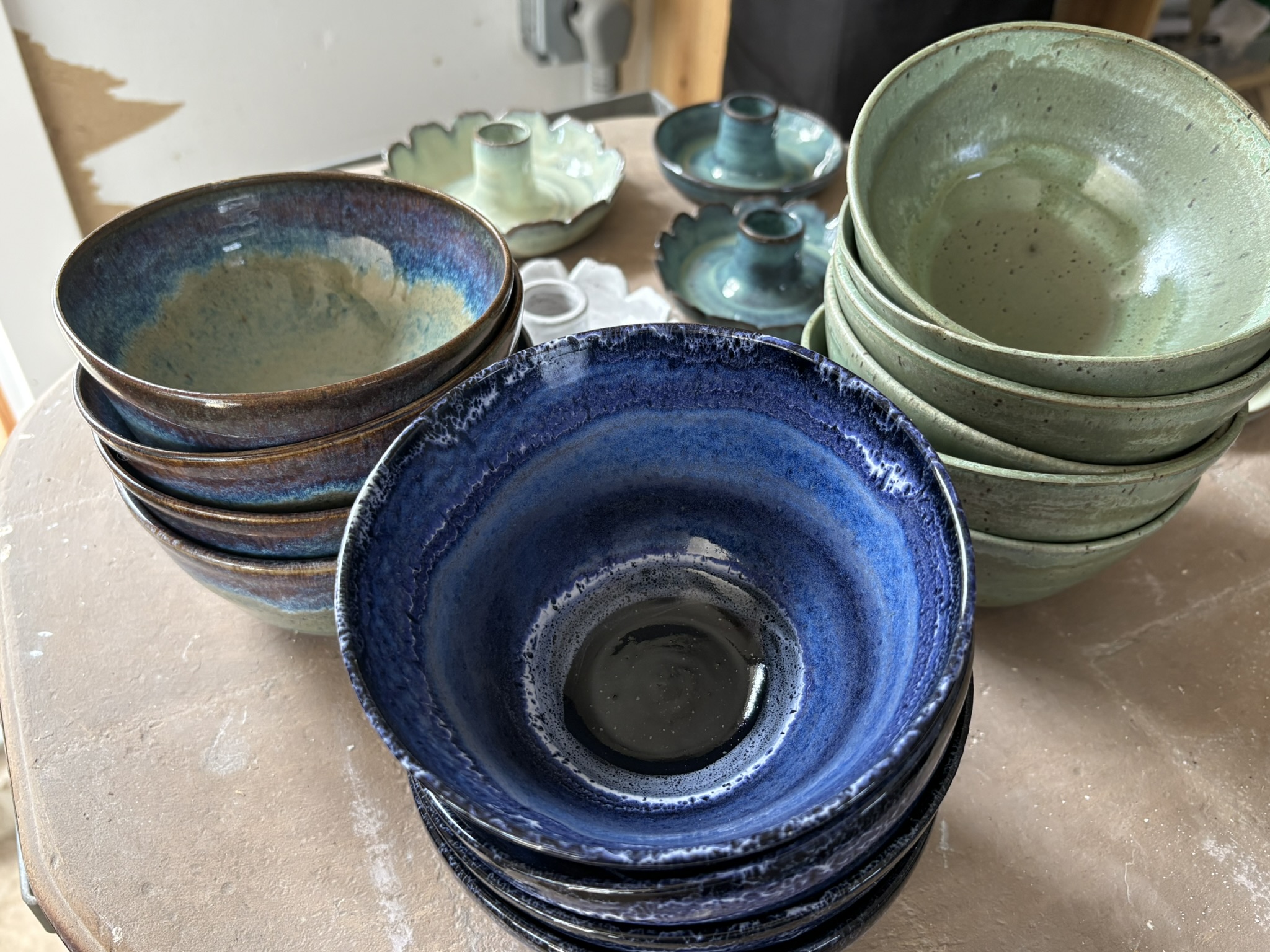 Stacks of handmade bowls in blue, green, and layered glazes
