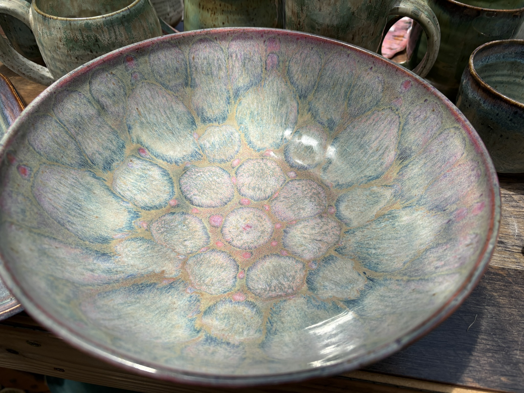 A broad handmade serving bowl with soft blue, pink, and green glaze patterns