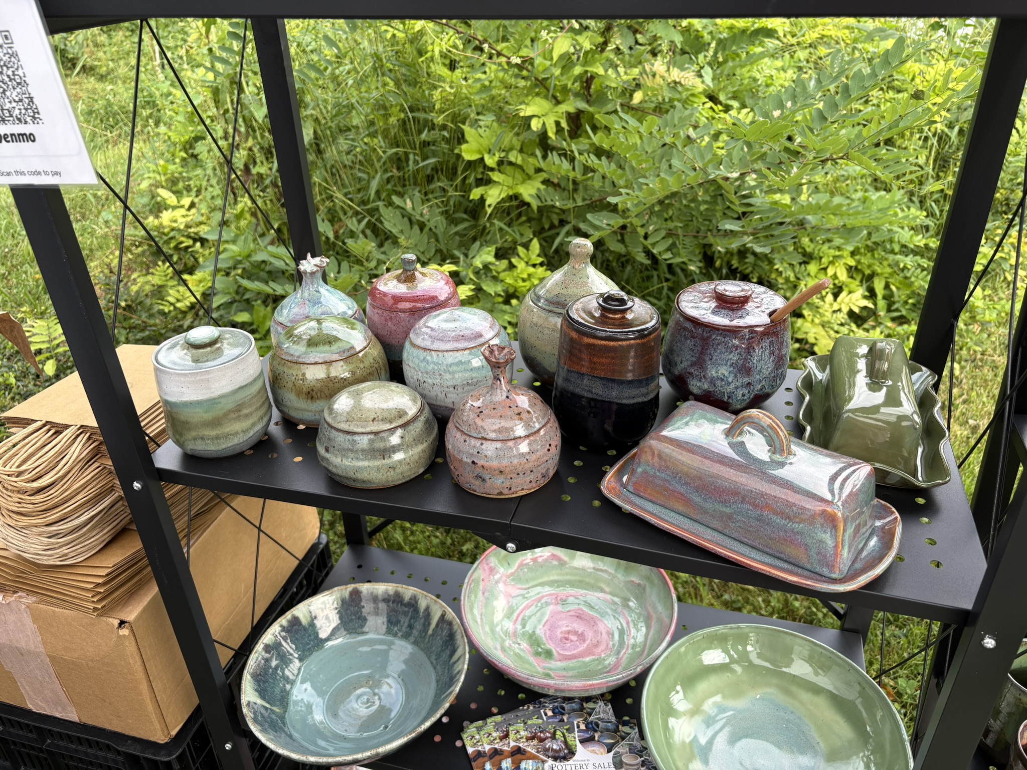 Glazed lidded jars, a butter dish, and bowls on shelves beside the garden
