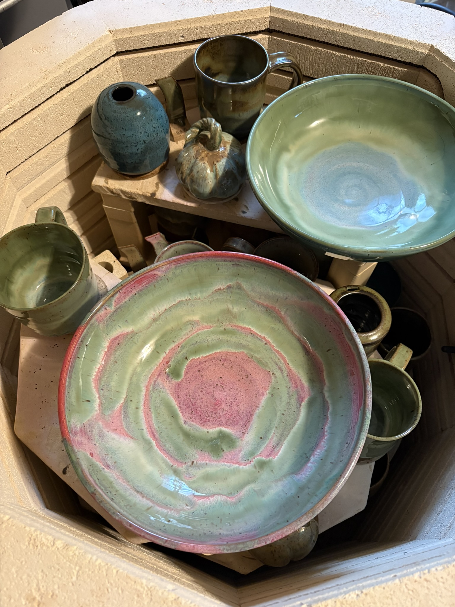 Freshly fired green and pink glazed bowls and small vessels in the kiln