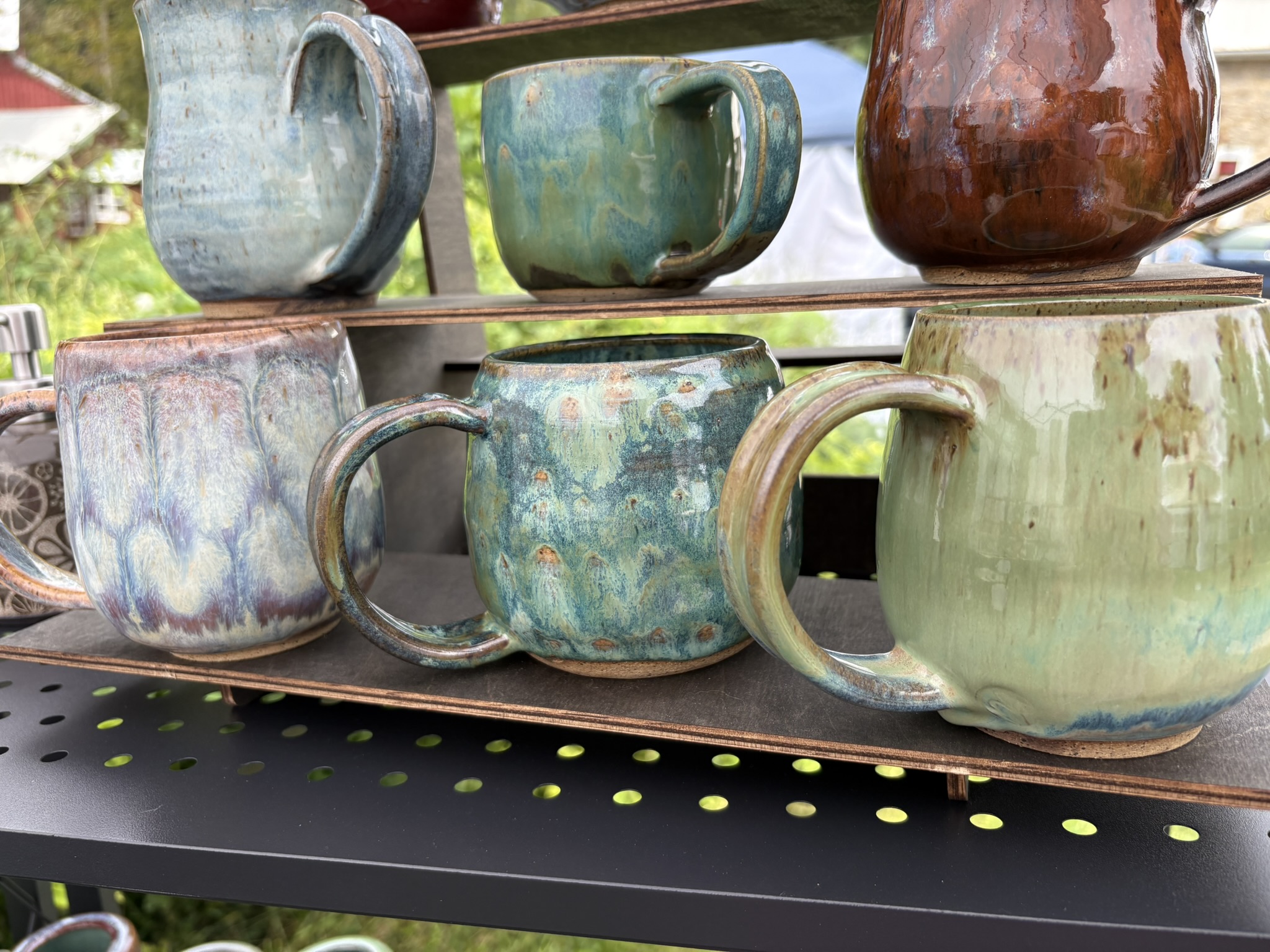 A shelf filled with handmade glazed mugs